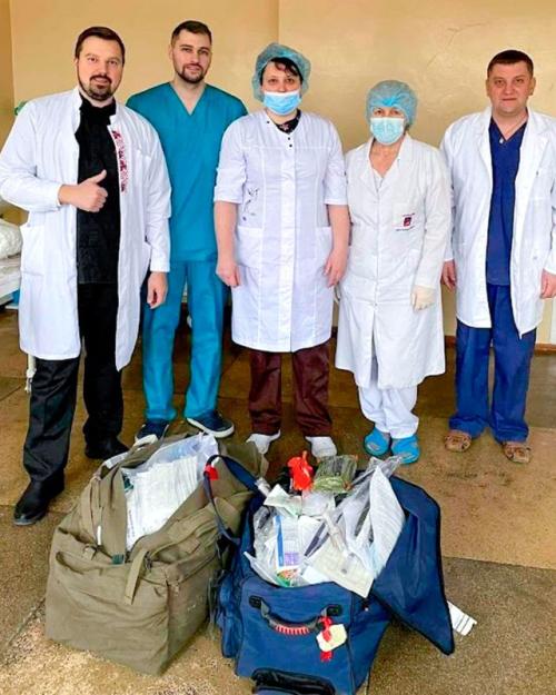 Five people in medical clothing show two bags of supplies