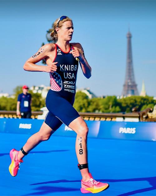 Person in racing gear runs on a blue pathway with the Eiffel Tower in the background