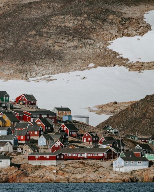 Hill with dozens of colorful houses on it, backed by a bleak landscape with snow